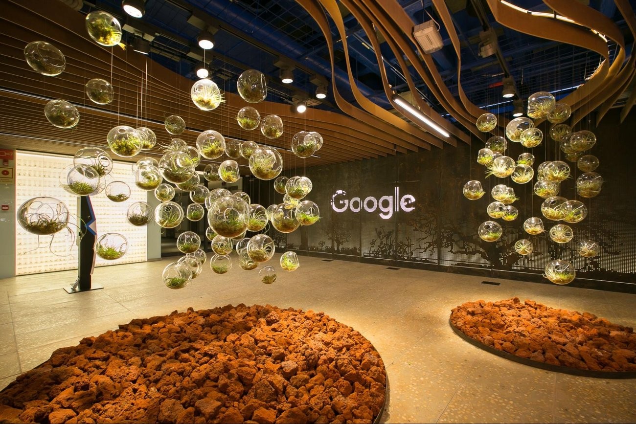 Hall do escritório do Google em Belo Horizonte, com esferas de vidro suspensas e o logo do Google na parede